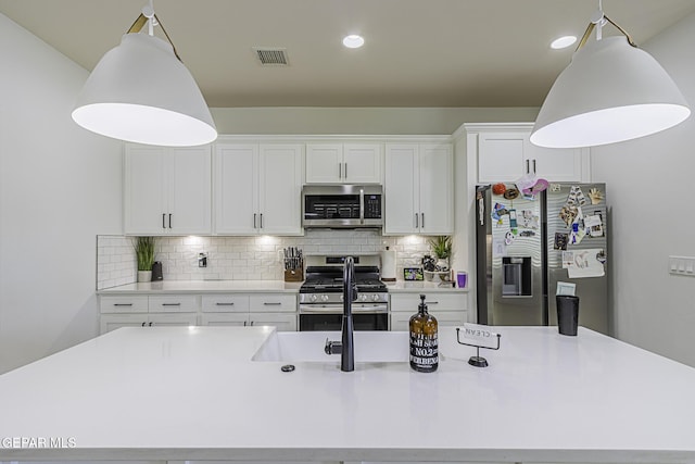 kitchen with stainless steel appliances, white cabinetry, backsplash, and decorative light fixtures