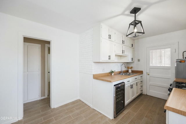 kitchen featuring white cabinets, sink, hanging light fixtures, range, and beverage cooler