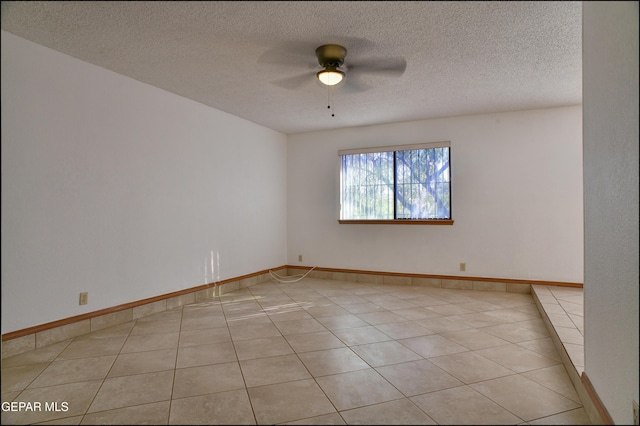 empty room featuring ceiling fan, light tile patterned flooring, and a textured ceiling