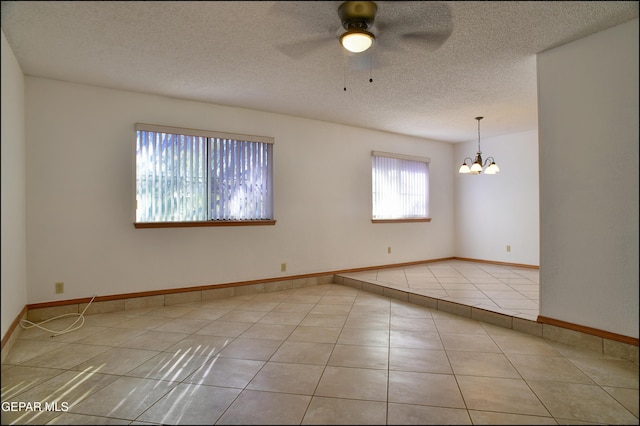 unfurnished room with ceiling fan with notable chandelier, a textured ceiling, and light tile patterned flooring