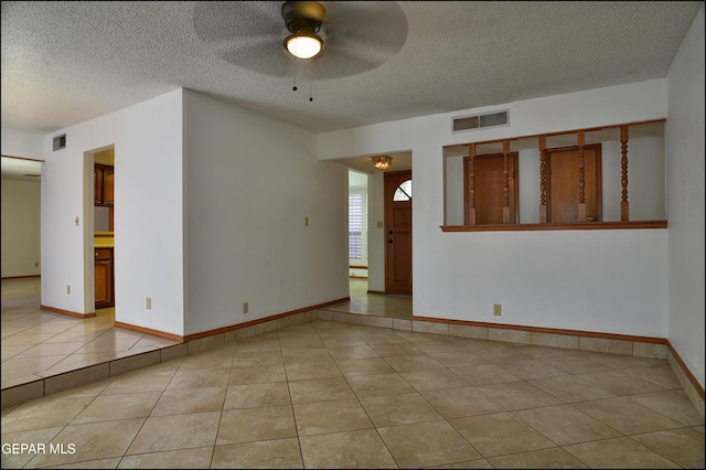 tiled empty room featuring a textured ceiling and ceiling fan