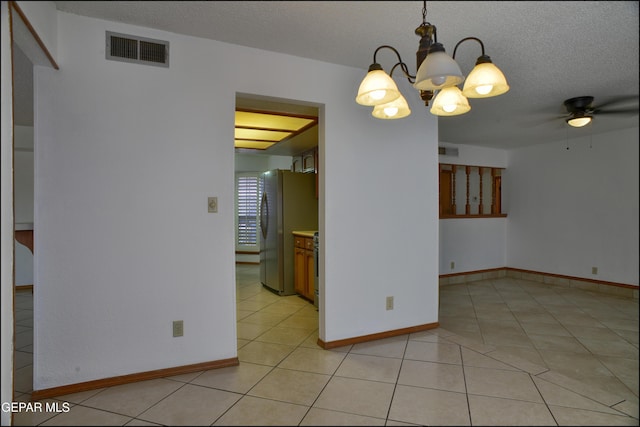 unfurnished dining area featuring light tile patterned floors, ceiling fan with notable chandelier, and a textured ceiling