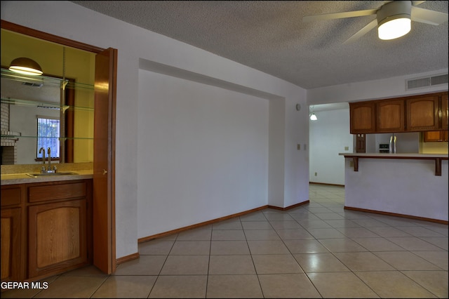 kitchen featuring ceiling fan, sink, stainless steel refrigerator with ice dispenser, a textured ceiling, and light tile patterned floors