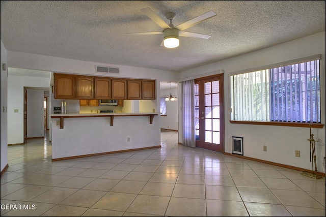 kitchen featuring hanging light fixtures, a kitchen bar, light tile patterned floors, ceiling fan with notable chandelier, and appliances with stainless steel finishes