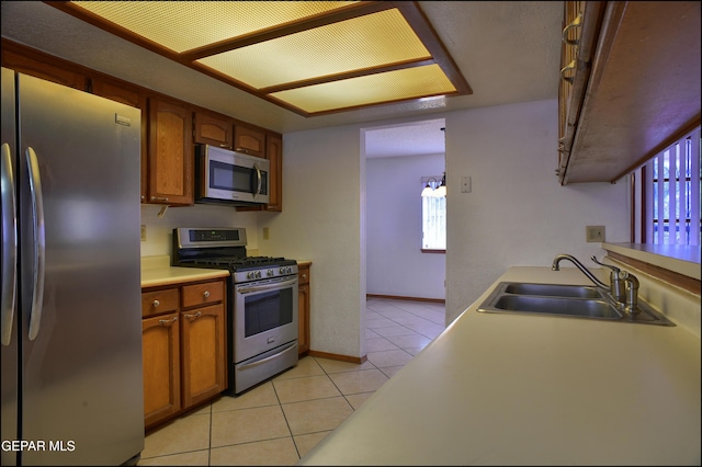 kitchen featuring decorative light fixtures, sink, light tile patterned floors, and stainless steel appliances