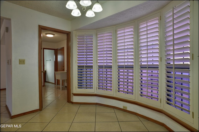 interior space featuring light tile patterned floors, a textured ceiling, and an inviting chandelier