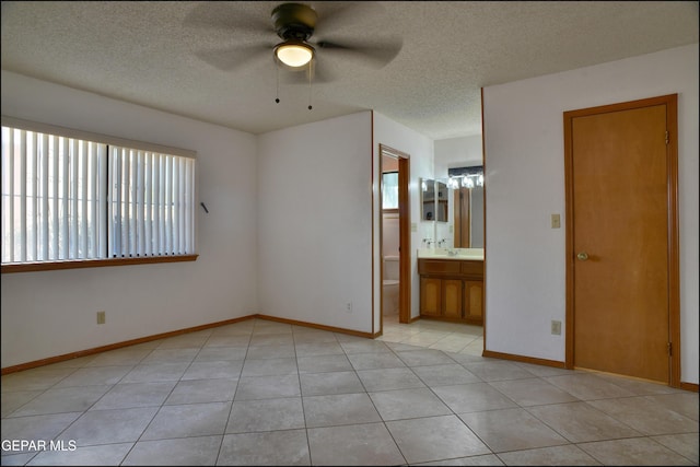 tiled empty room with a textured ceiling, ceiling fan, a healthy amount of sunlight, and sink