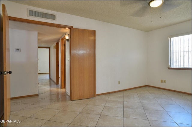 tiled empty room with ceiling fan and a textured ceiling