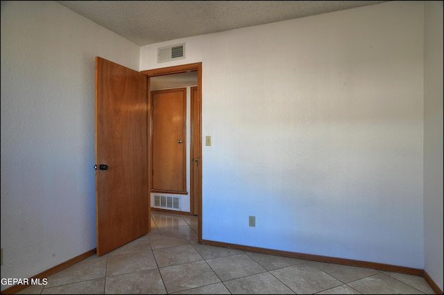 unfurnished room with light tile patterned floors and a textured ceiling