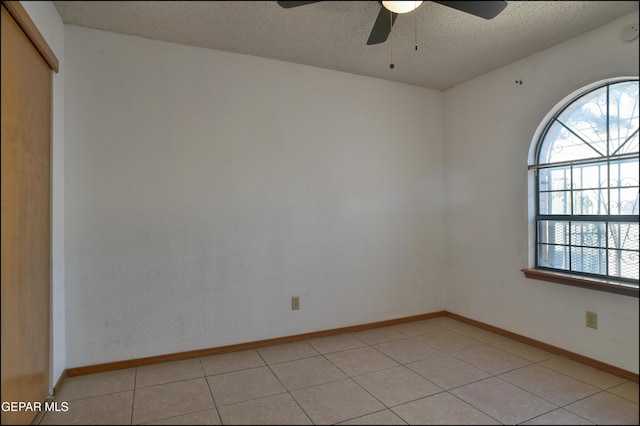 tiled empty room featuring a textured ceiling and ceiling fan