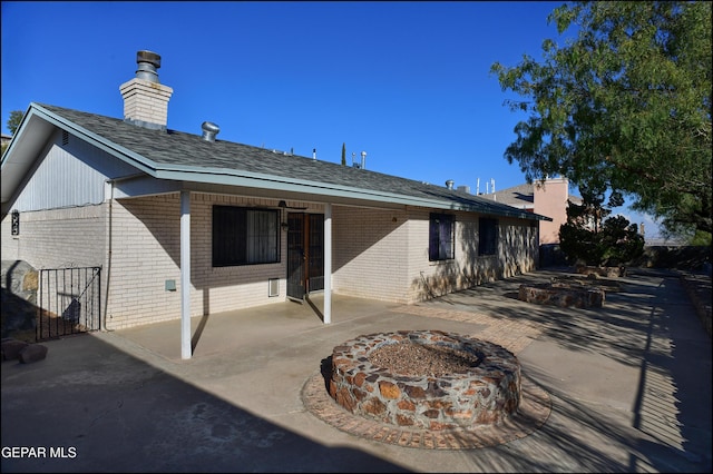 back of property with a fire pit and a patio area