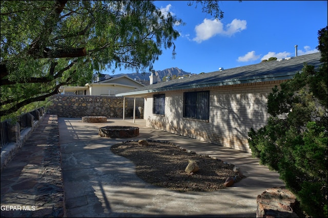 back of property featuring a fire pit, a mountain view, and a patio