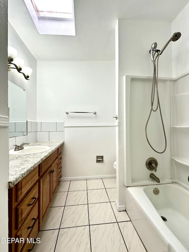 full bathroom with a skylight, vanity, tub / shower combination, and toilet