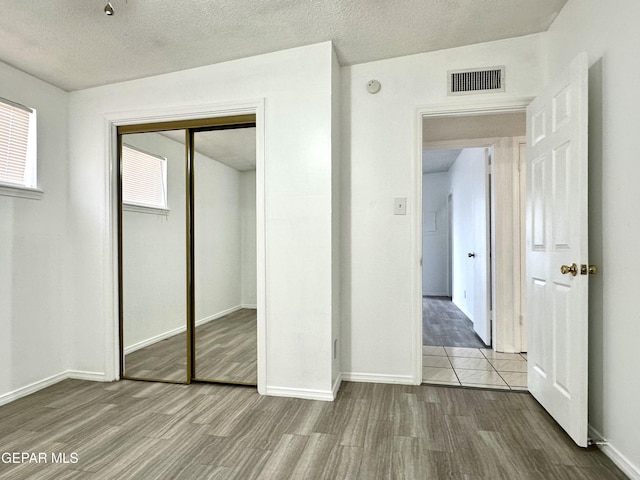 unfurnished bedroom featuring a textured ceiling, hardwood / wood-style flooring, and a closet