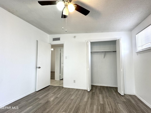 unfurnished bedroom with a textured ceiling, ceiling fan, a closet, and dark hardwood / wood-style floors