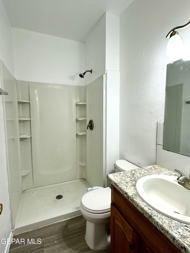 bathroom with toilet, a shower, wood-type flooring, and vanity