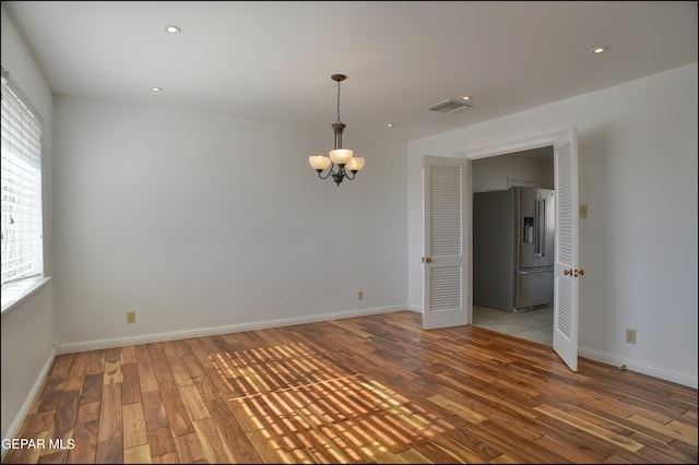 spare room featuring a chandelier and wood-type flooring