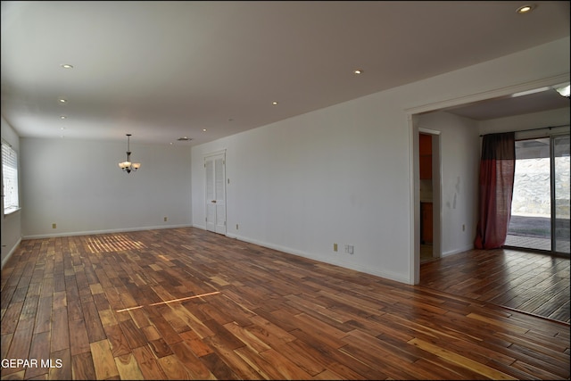 empty room featuring dark hardwood / wood-style flooring and a chandelier