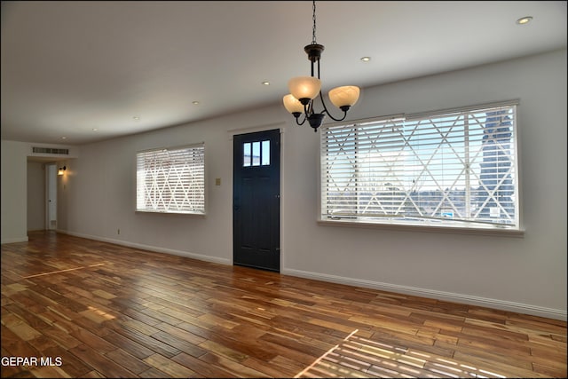 foyer entrance with dark hardwood / wood-style floors and an inviting chandelier