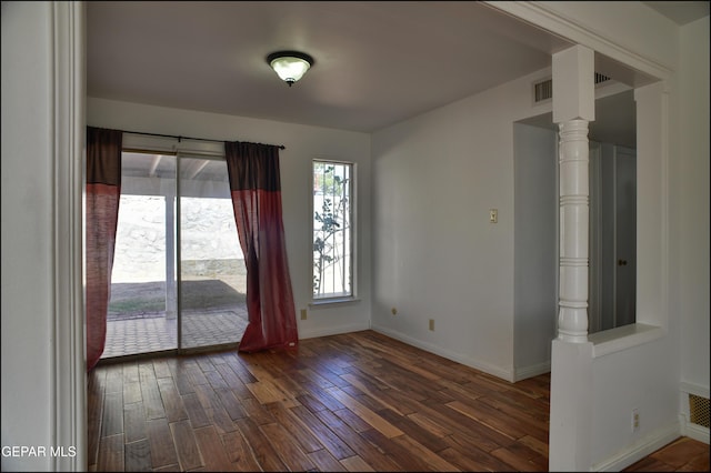 empty room with dark hardwood / wood-style flooring and decorative columns