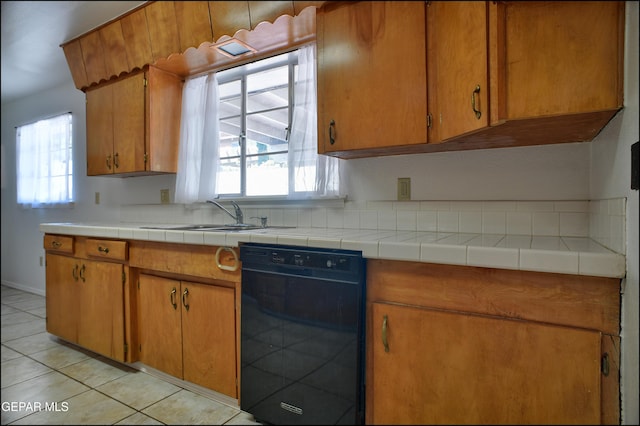 kitchen with light tile patterned floors, black dishwasher, plenty of natural light, and sink