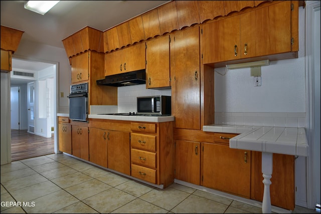 kitchen featuring light tile patterned floors, backsplash, and oven