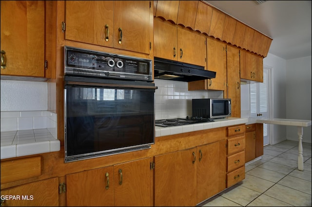 kitchen with tile countertops, oven, gas stovetop, and light tile patterned floors