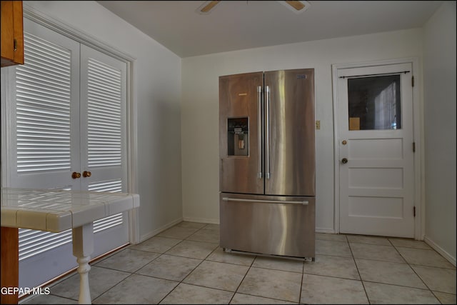 kitchen featuring stainless steel fridge with ice dispenser, tile countertops, light tile patterned floors, and ceiling fan