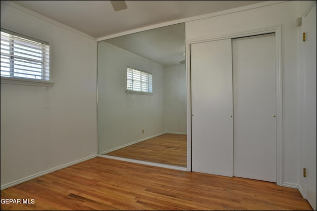 unfurnished bedroom featuring multiple windows, ceiling fan, light hardwood / wood-style flooring, and ornamental molding