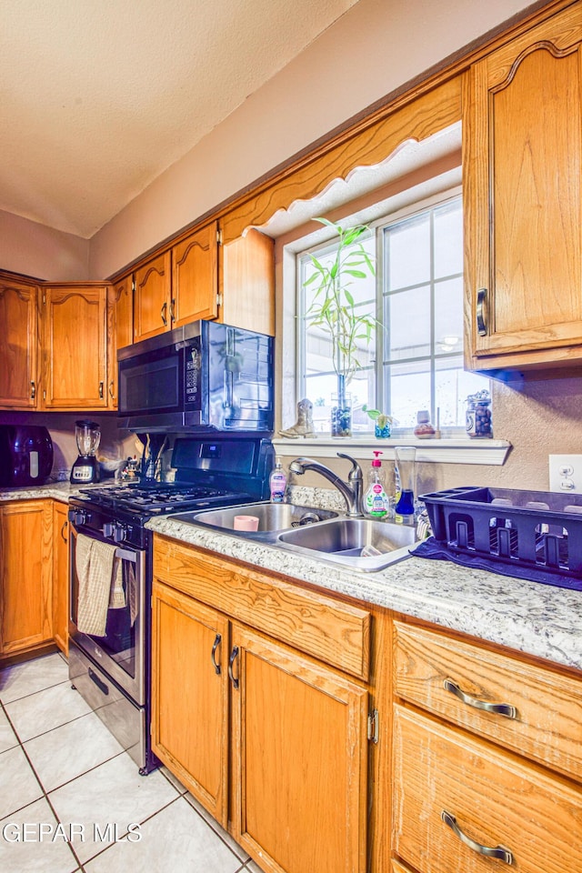 kitchen featuring a textured ceiling, light tile patterned flooring, sink, and stainless steel appliances