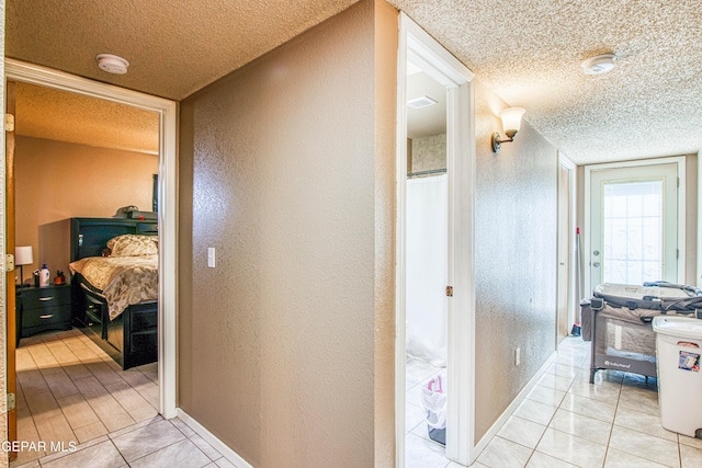 hall with light tile patterned floors and a textured ceiling