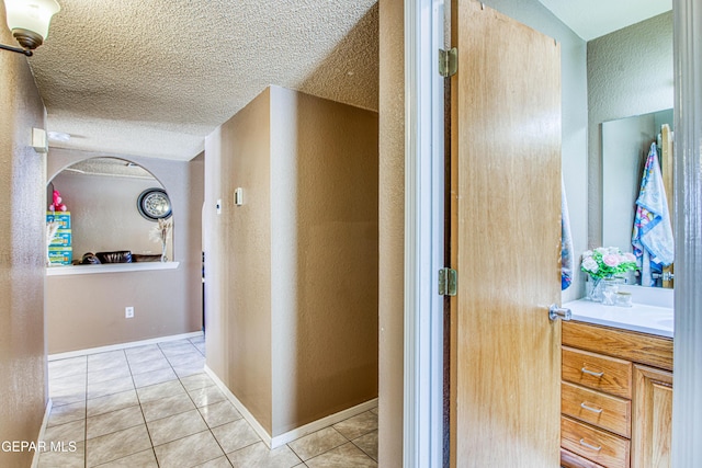 hallway featuring light tile patterned floors and a textured ceiling