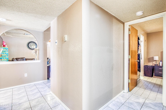 corridor with light tile patterned flooring and a textured ceiling