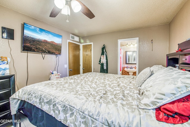 bedroom with ceiling fan, a textured ceiling, and ensuite bath