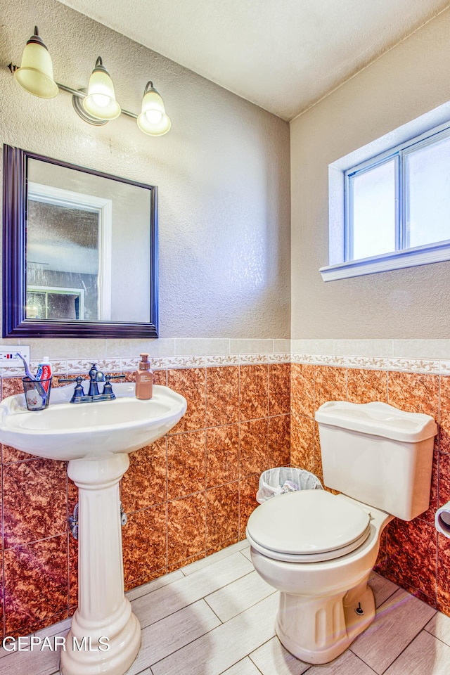 bathroom featuring toilet and tile walls