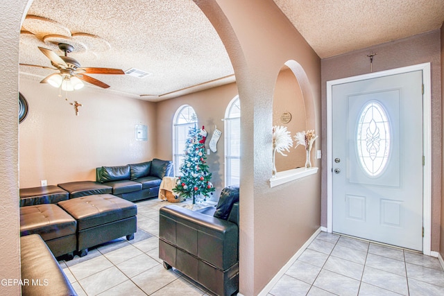 foyer entrance with light tile patterned floors, a textured ceiling, and a wealth of natural light