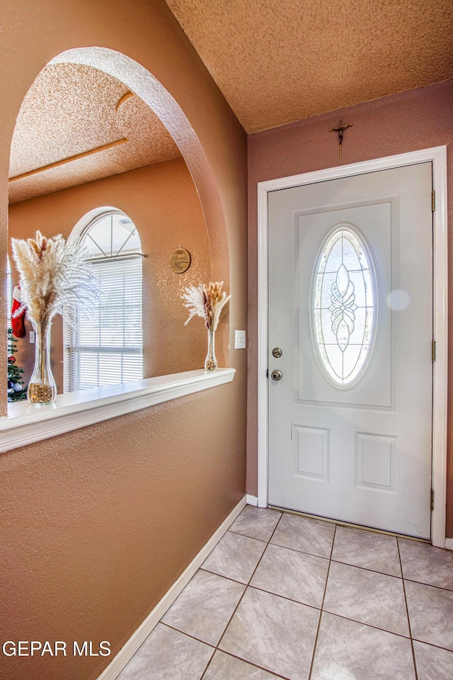 foyer entrance with light tile patterned floors and a textured ceiling