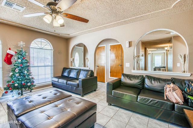 living room with a textured ceiling, ceiling fan, and light tile patterned flooring