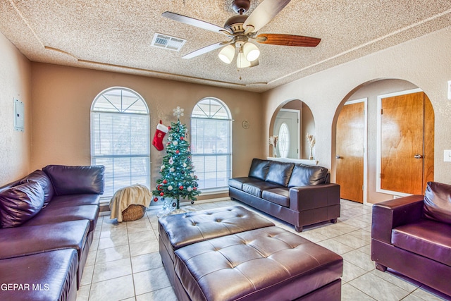 tiled living room with plenty of natural light, ceiling fan, and a textured ceiling