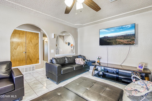 living room with tile patterned flooring, ceiling fan, and a textured ceiling