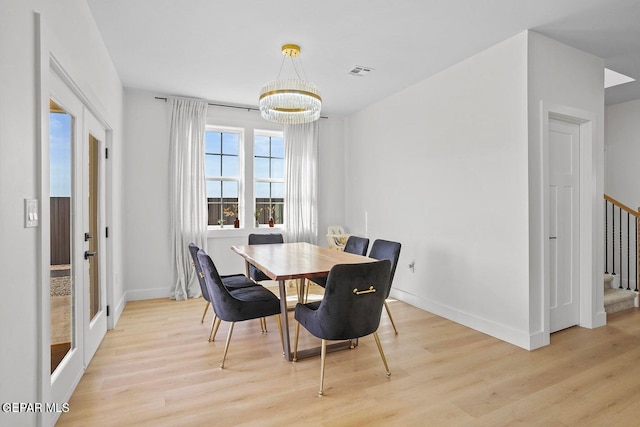 dining room with french doors, light hardwood / wood-style floors, and a notable chandelier