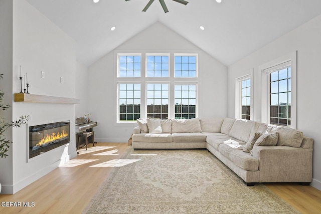 living room with ceiling fan, high vaulted ceiling, and light hardwood / wood-style flooring