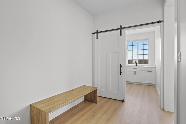 mudroom featuring a barn door, sink, and light hardwood / wood-style floors