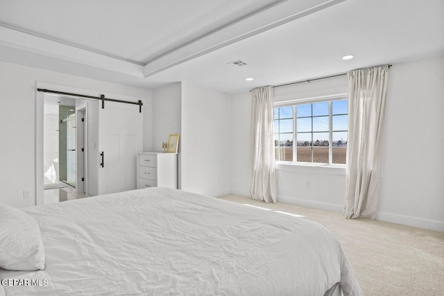 bedroom featuring a barn door, light colored carpet, and ensuite bath