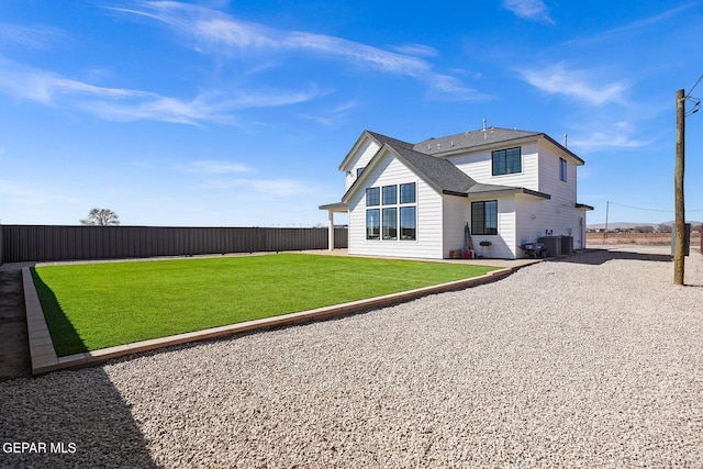 rear view of property featuring central AC unit and a lawn