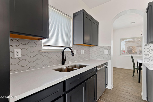 kitchen featuring stainless steel dishwasher, decorative backsplash, sink, and light hardwood / wood-style flooring