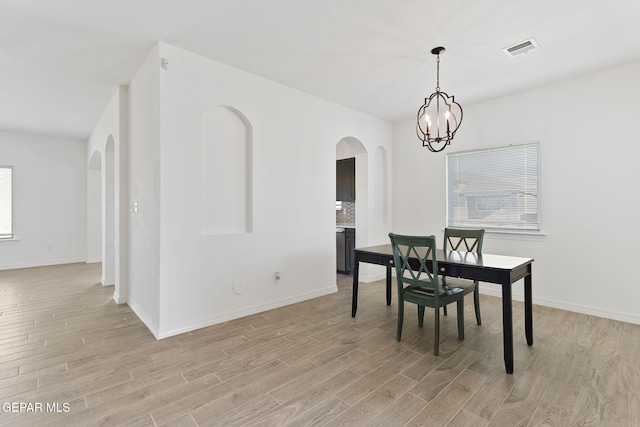 dining room featuring light wood-type flooring and an inviting chandelier