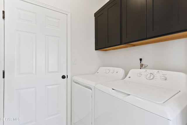 clothes washing area with cabinets and washing machine and clothes dryer