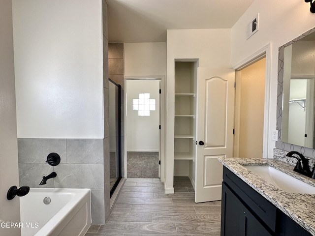 bathroom featuring hardwood / wood-style flooring, vanity, and plus walk in shower