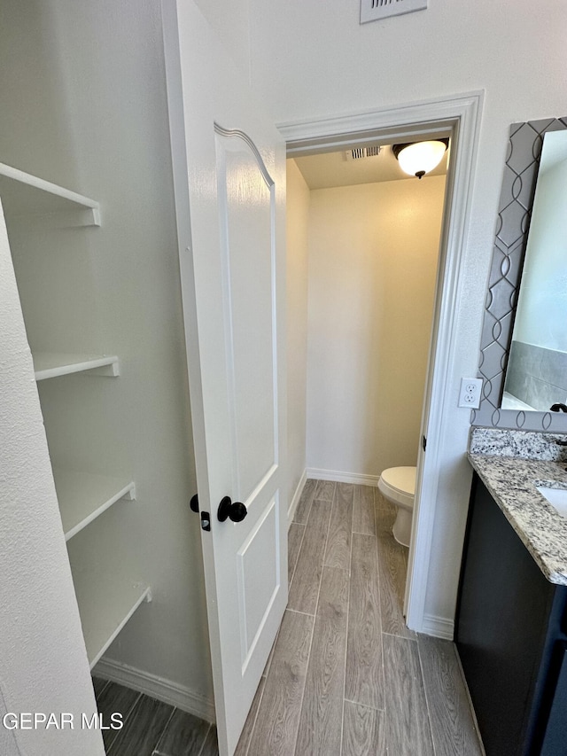 bathroom featuring wood-type flooring, vanity, and toilet